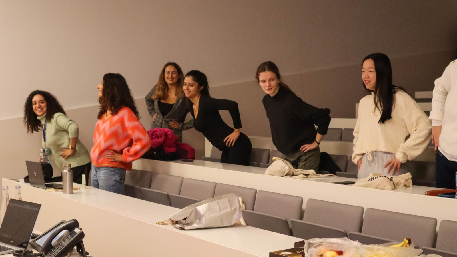 A few people doing a warm up exercise in a classroom.