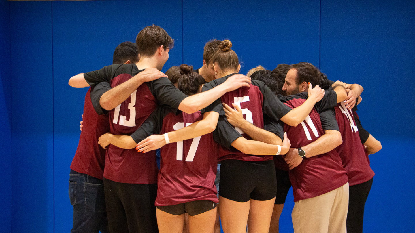 A picture of a volleyball team hugging.