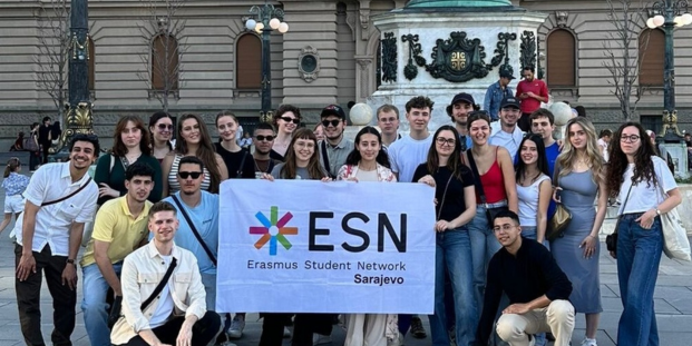 A group of young people posing for a picture with an ESN Sarajevo flag